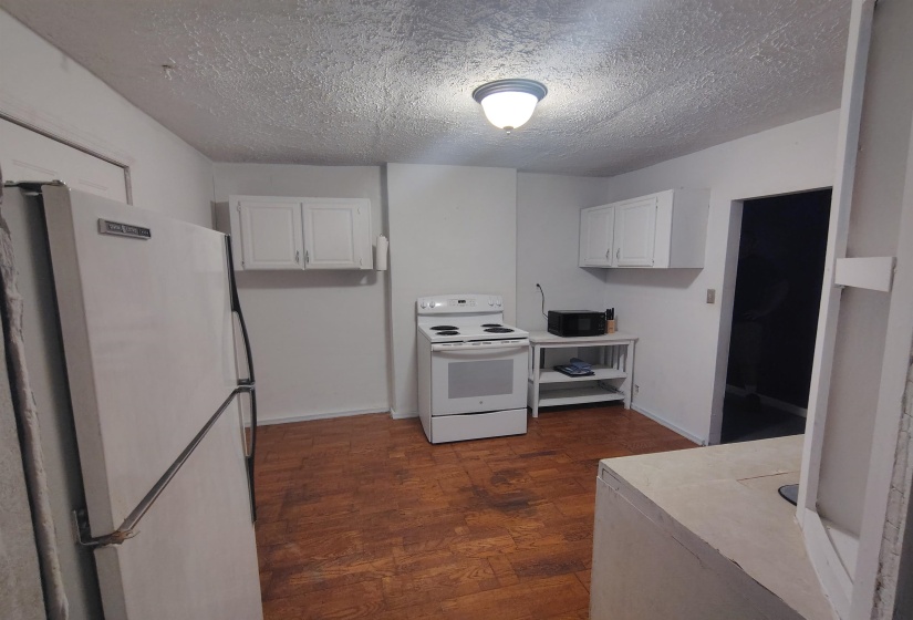 Kitchen featuring wood-finish flooring, white cabinetry, and white appliances including a refrigerator and range