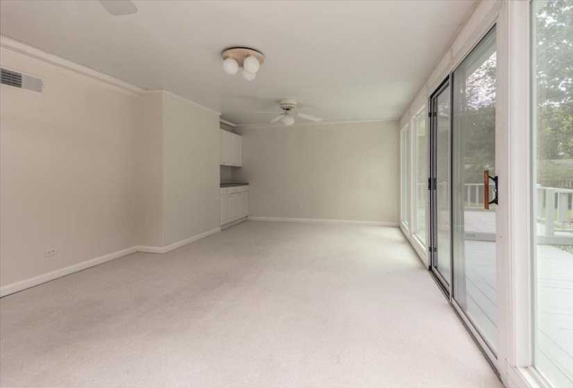 Room with a wall of sliding glass doors opening onto a deck