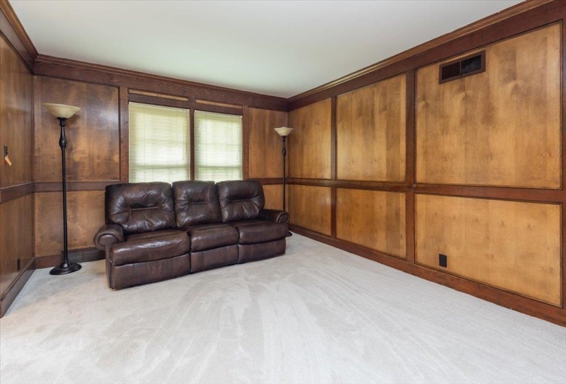 Room with paneled wood-finish walls, crown molding, and light-colored carpeting