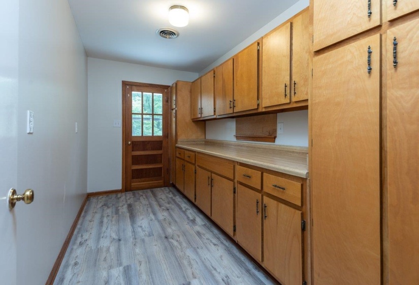 Kitchen featuring extensive light wood cabinetry, laminate countertops, wood-finish flooring, and a glass-paneled door