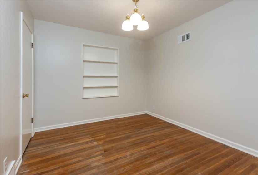 Bright interior space featuring wood-finish flooring, white baseboards, and a built-in recessed shelving unit