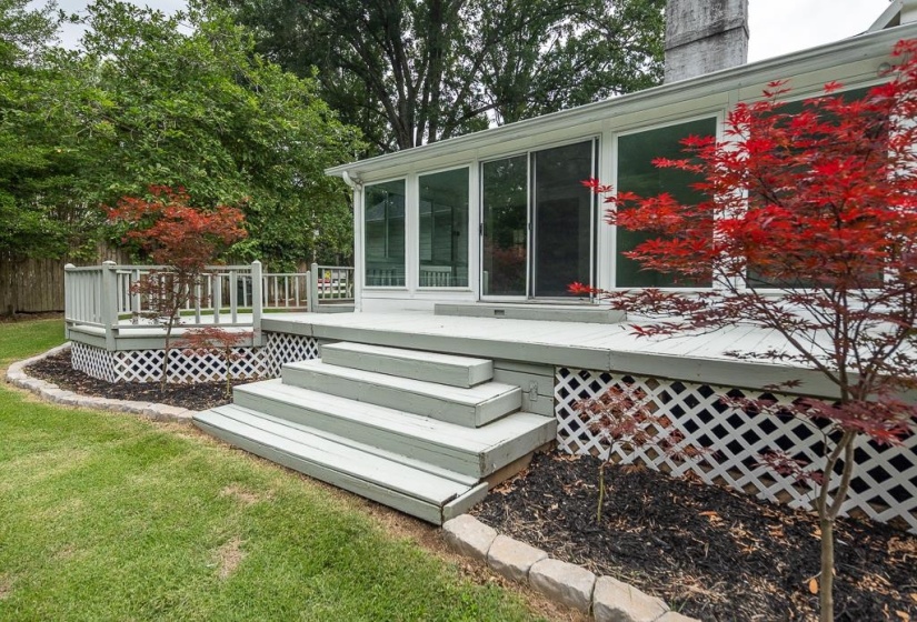 Expansive rear deck featuring multiple steps, white lattice skirting, and a railing system