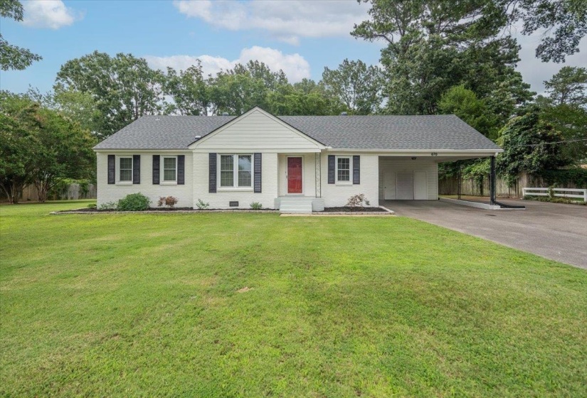 White brick single-story residence featuring a dark shingle roof, red entry door, and black window shutters
