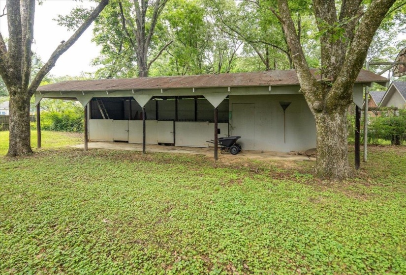 Freestanding outbuilding featuring a covered porch, multiple partitioned bays, and a side-entry door