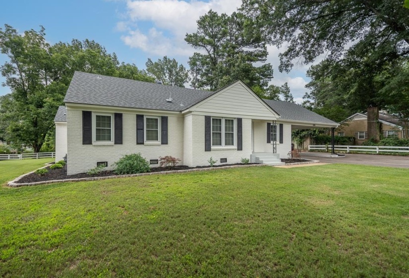 White brick exterior with dark shutters, gabled roofline, and attached carport