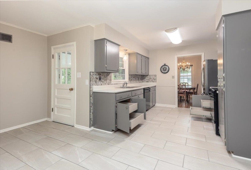 Kitchen featuring light-toned tile flooring, grey cabinetry, a patterned backsplash, and light countertops