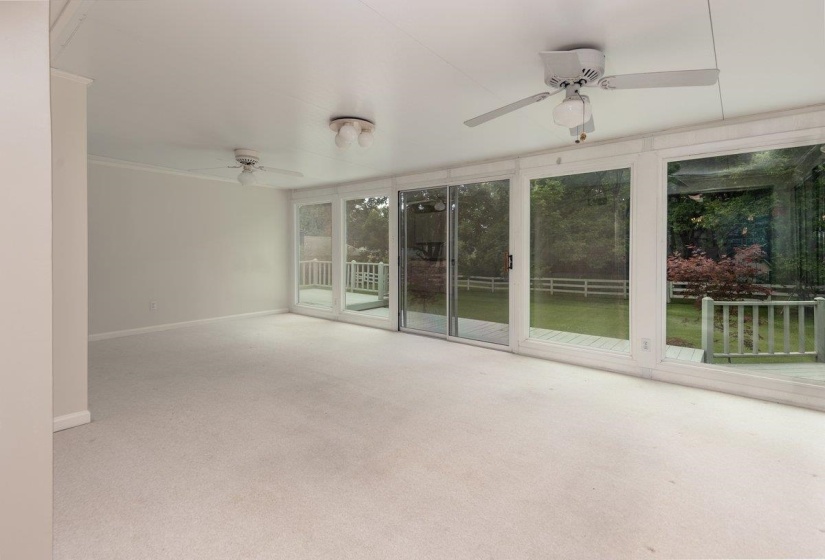 Spacious interior room with light-toned carpeting and multiple ceiling fans