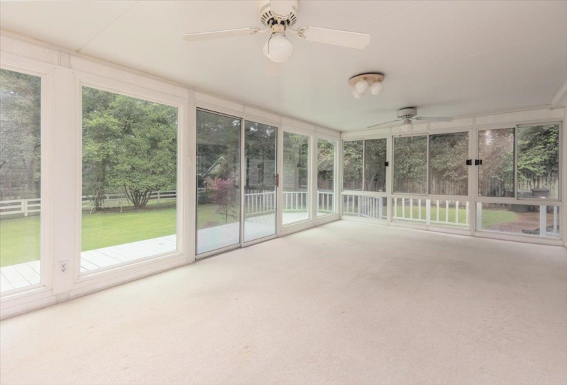 Carpeted sunroom featuring multiple large windows and sliding glass doors