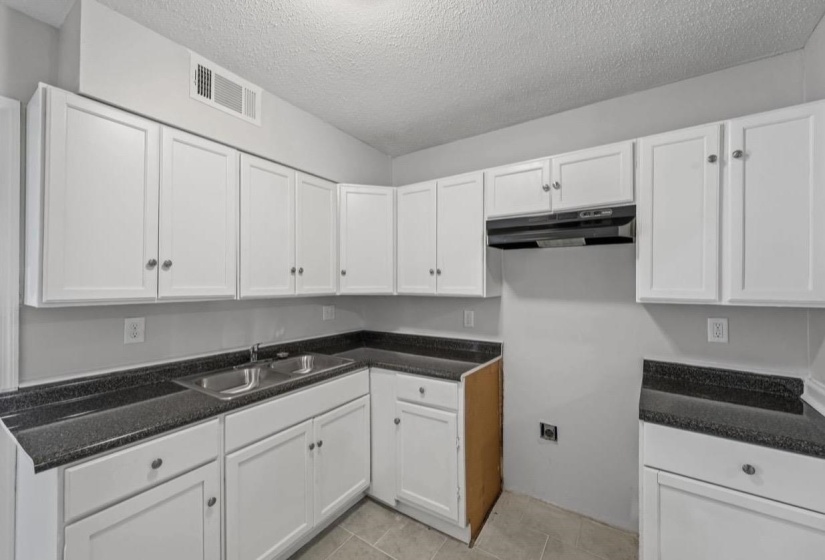 Kitchen featuring white cabinetry, dark speckled countertops, and a double basin stainless steel sink