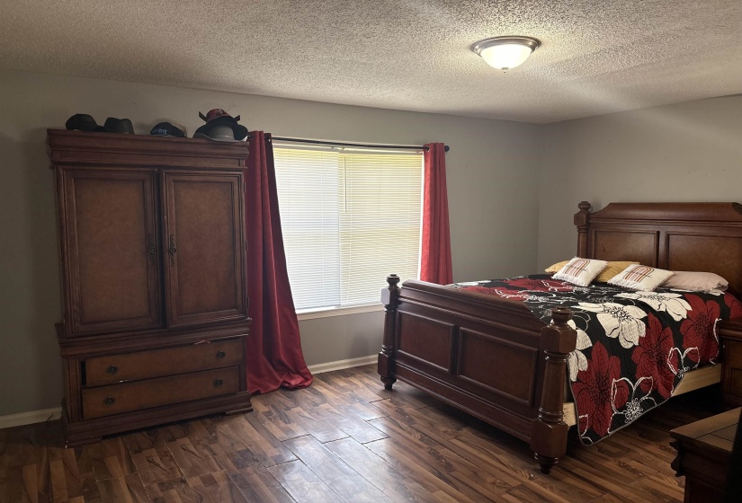 Room featuring wood-finish flooring, a window with horizontal blinds, and a flush mount ceiling light fixture