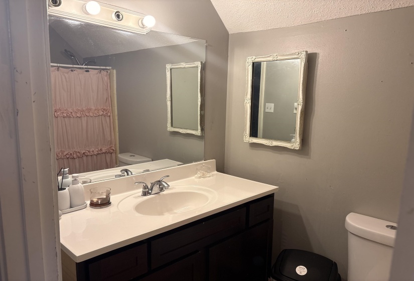 Bathroom featuring a vanity with a white countertop and dark wood-finish cabinetry, an oval undermount sink, and a chrome faucet