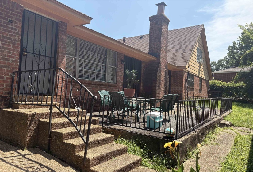 Rear exterior featuring a brick facade and a raised wooden deck with black metal railing