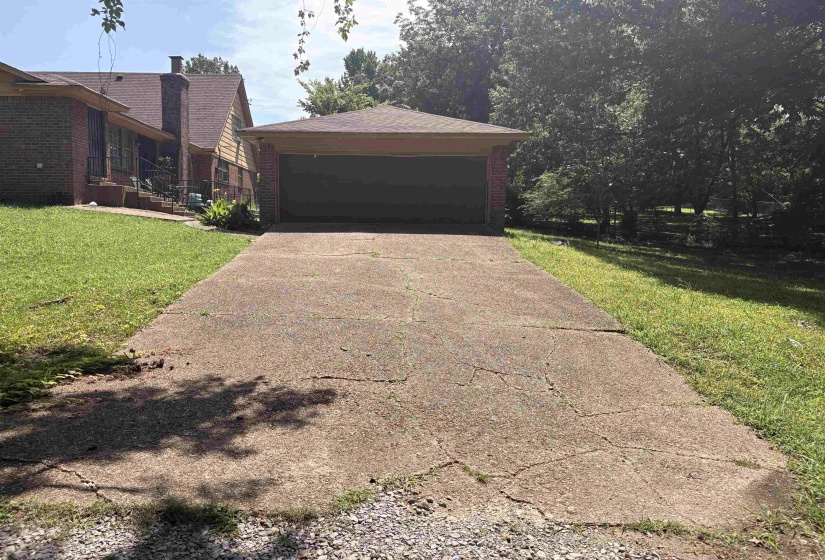 Attached garage with a dark panel door, set back from a concrete driveway