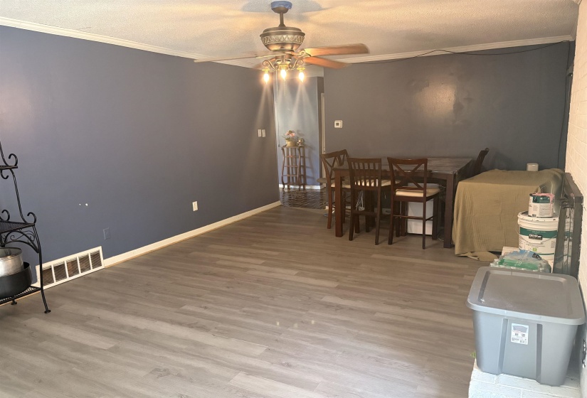 Spacious room featuring wood-finish flooring, crown molding, and a ceiling fan with integrated lighting