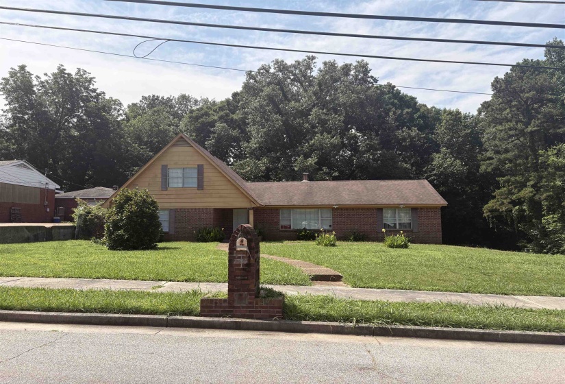 Brick facade home featuring a prominent gabled section with vertical siding
