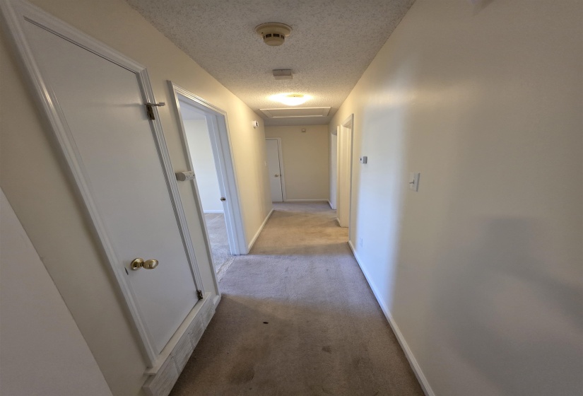 Hallway featuring neutral-toned walls, recessed lighting, and light-colored carpeting