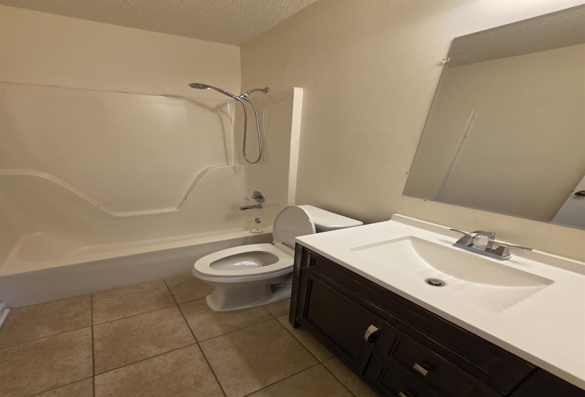 Bathroom featuring a dark wood-finish vanity with an integrated white sink, a chrome faucet, and a large wall-mounted mirror