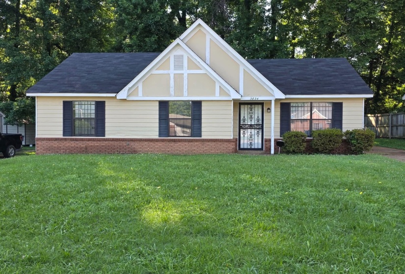 Single-story residence featuring a gabled roofline, light-colored siding, and a brick foundation