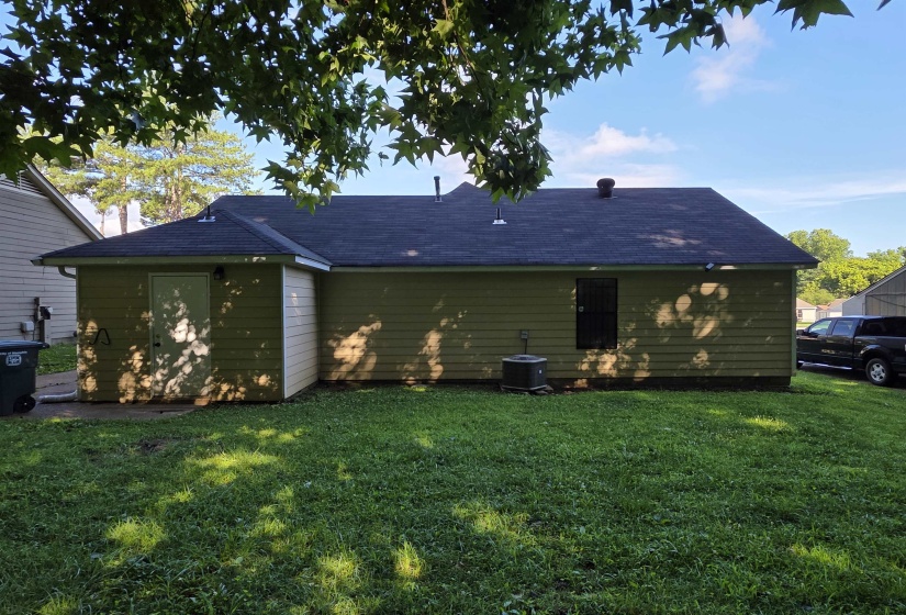 Rear elevation featuring light-colored horizontal siding and a dark shingle roof