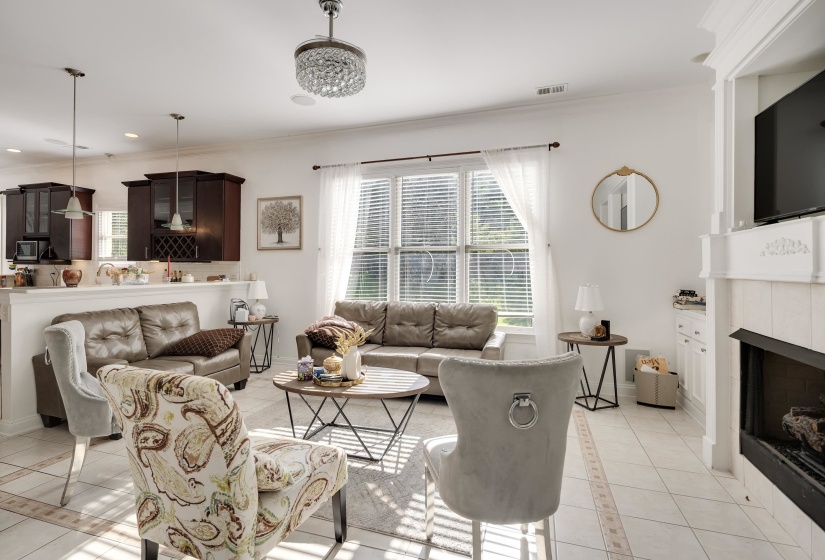 Spacious living area featuring tile flooring, a fireplace with a white mantel, and multiple windows