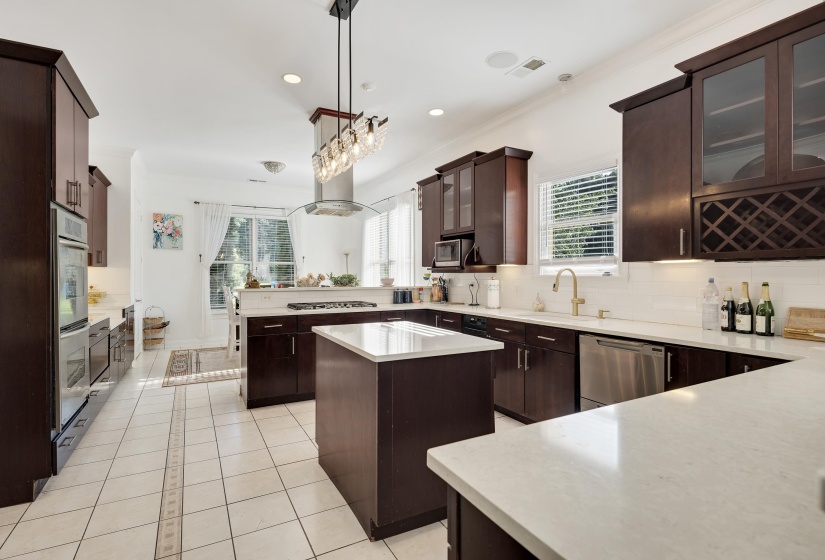 Kitchen featuring dark wood cabinetry, light tile flooring, white countertops, built-in double ovens, and stainless steel appliances