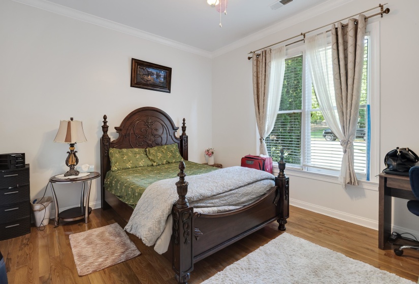 Bright interior room featuring wood-finish flooring, white walls, and crown molding