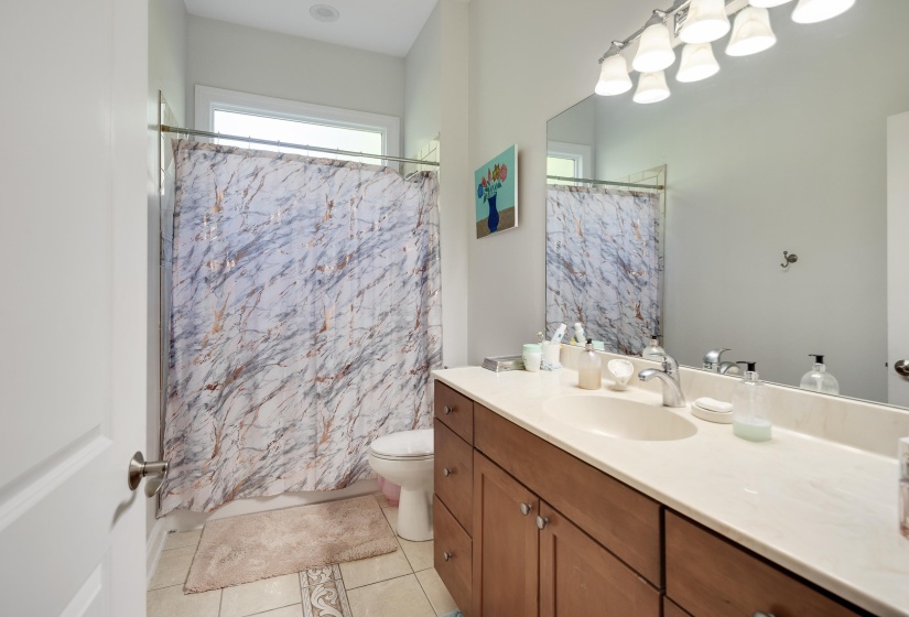 Full bathroom featuring a single vanity with wood-finish cabinetry, a light-toned countertop, and an integrated sink