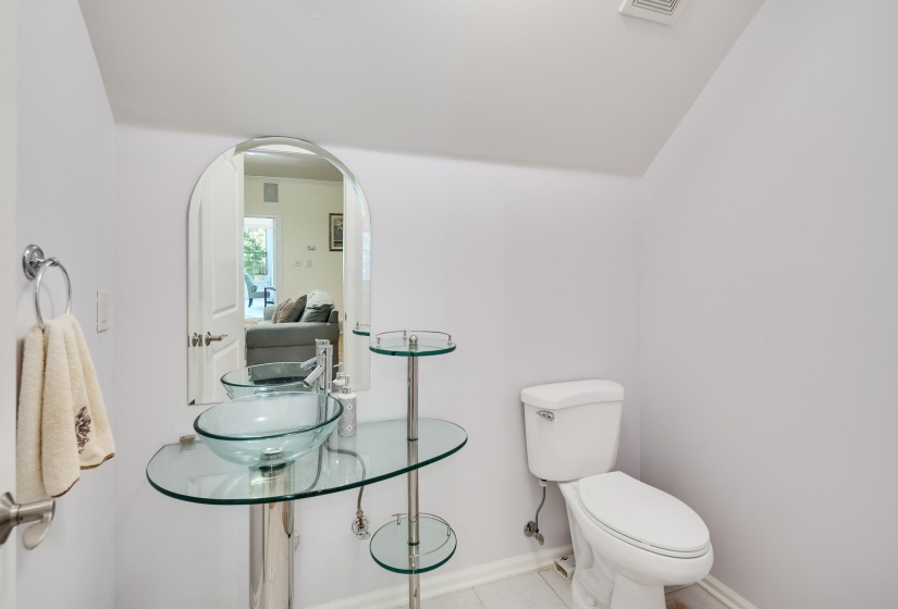 Powder room featuring a contemporary glass vessel sink, chrome pedestal, and an arched mirror