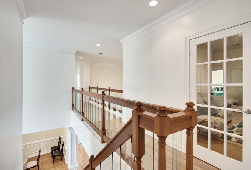 Upper-level hallway featuring wood-finish flooring, recessed lighting, crown molding, and a French door with clear glass panels