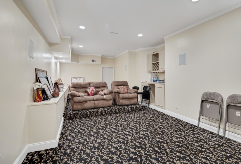 Finished lower level featuring recessed lighting, crown molding, a built-in wet bar with cabinetry, and a raised seating area