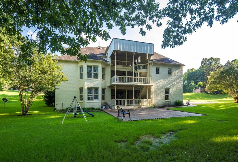 Expansive rear exterior featuring a two-story residence with multiple balconies and a ground-level patio