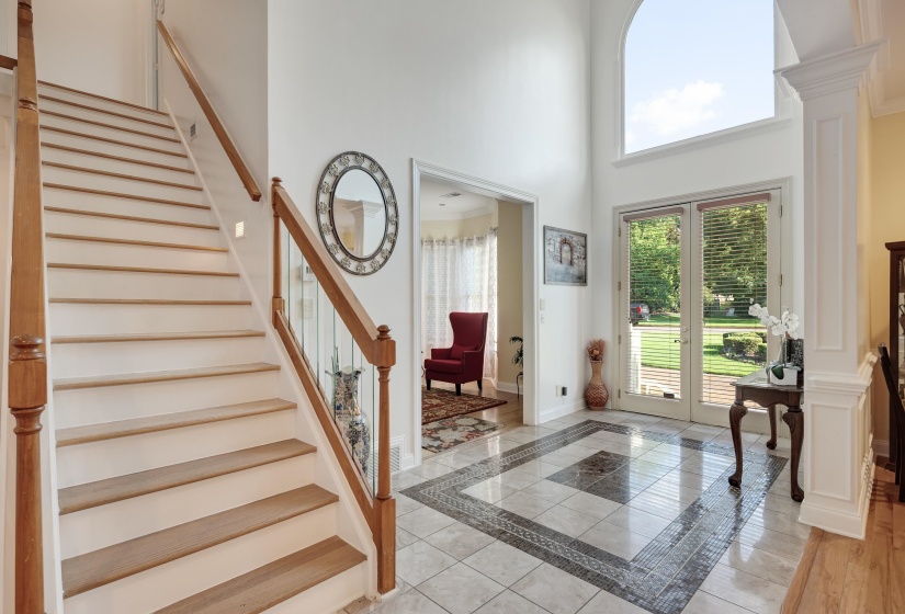 Two-story entryway featuring a grand staircase with wood railings and glass balusters