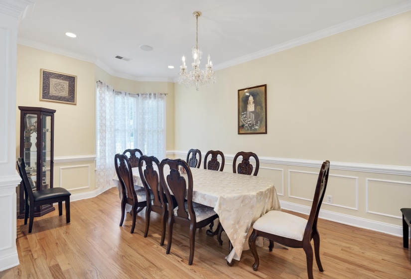 Dining space featuring hardwood flooring, a crystal chandelier, recessed lighting, and decorative wall molding