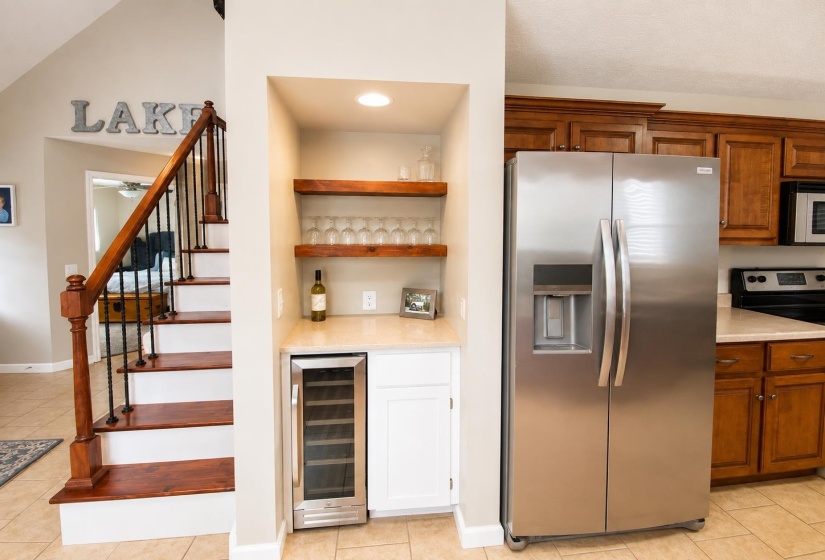 Built-in bar niche featuring floating wood shelves, recessed lighting, and a wine refrigerator