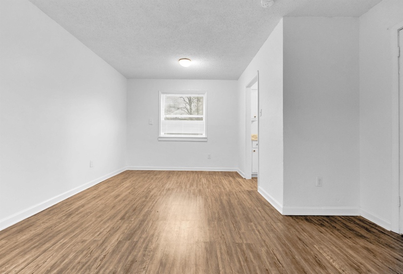 Spacious room featuring wood-finish flooring, white baseboards, and a neutral wall palette