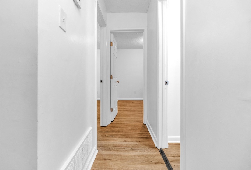 Interior hallway with wood-finish flooring, white walls, and white trim