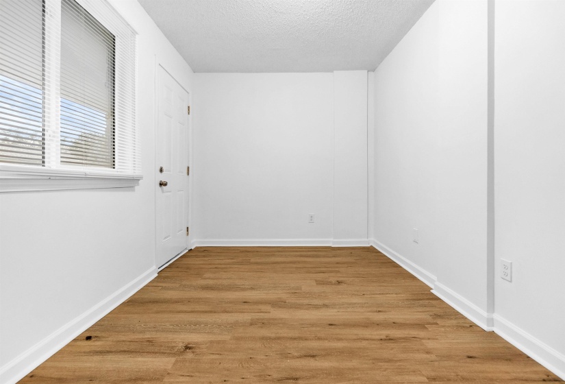 Room featuring wood-finish flooring, white baseboards, and bright white walls