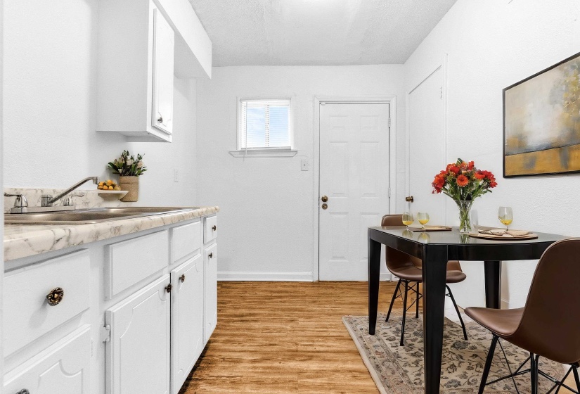 Compact kitchen featuring white cabinetry with dark hardware and a stainless steel sink