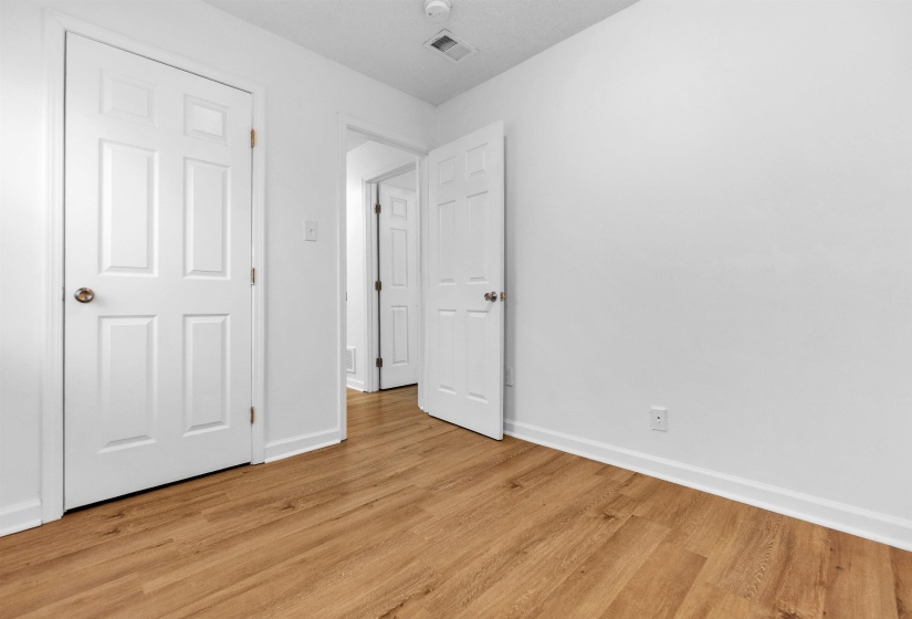Room featuring wood-finish flooring, white walls, and white baseboards