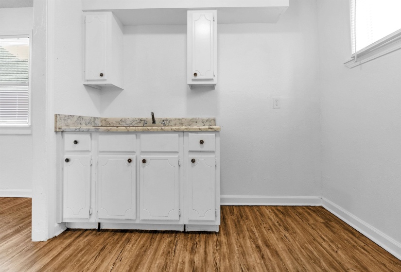 Wood-finish flooring complementing a white cabinetry run with a light-toned countertop and sink