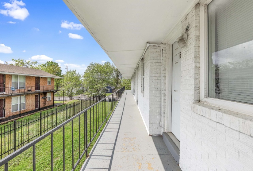 Exterior balcony with white painted brick siding and black metal railings