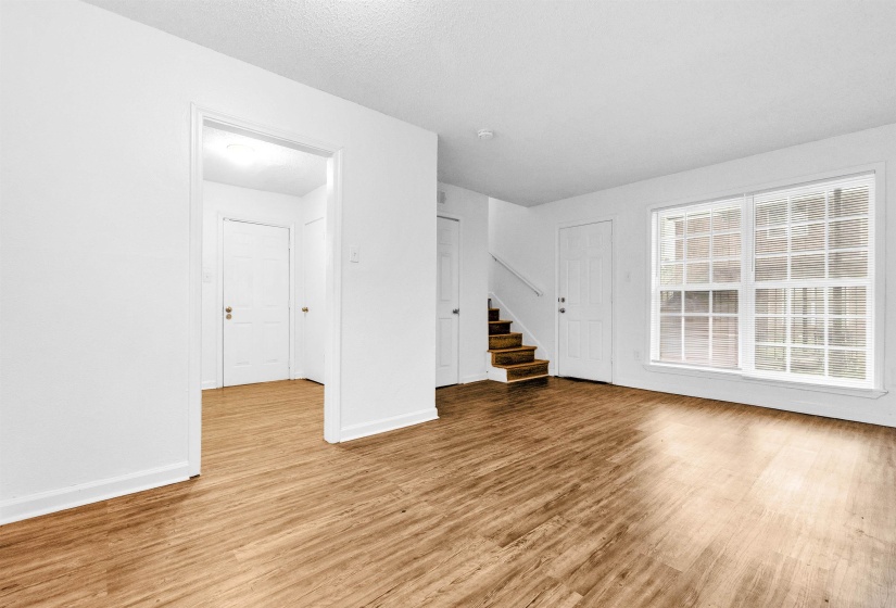 Spacious interior featuring wood-finish flooring, white walls, and a prominent window with grid detailing