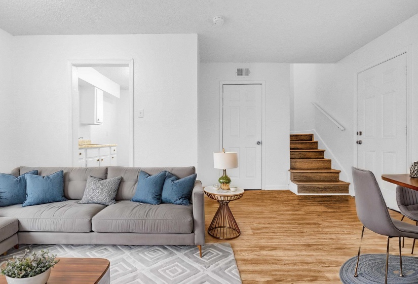 Bright interior space featuring wood-finish flooring, a staircase with a white handrail, and white paneled doors