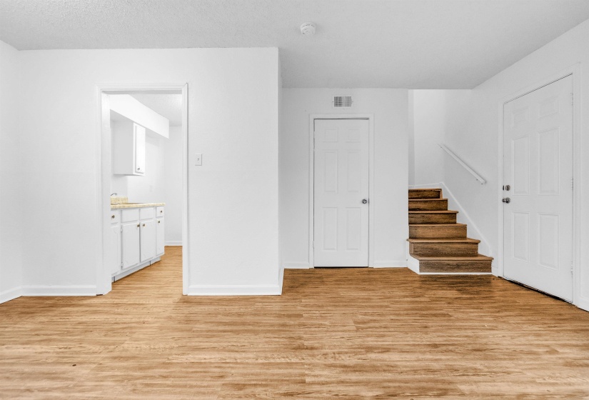 Expansive living area featuring wood-finish flooring, white walls, and bright baseboards