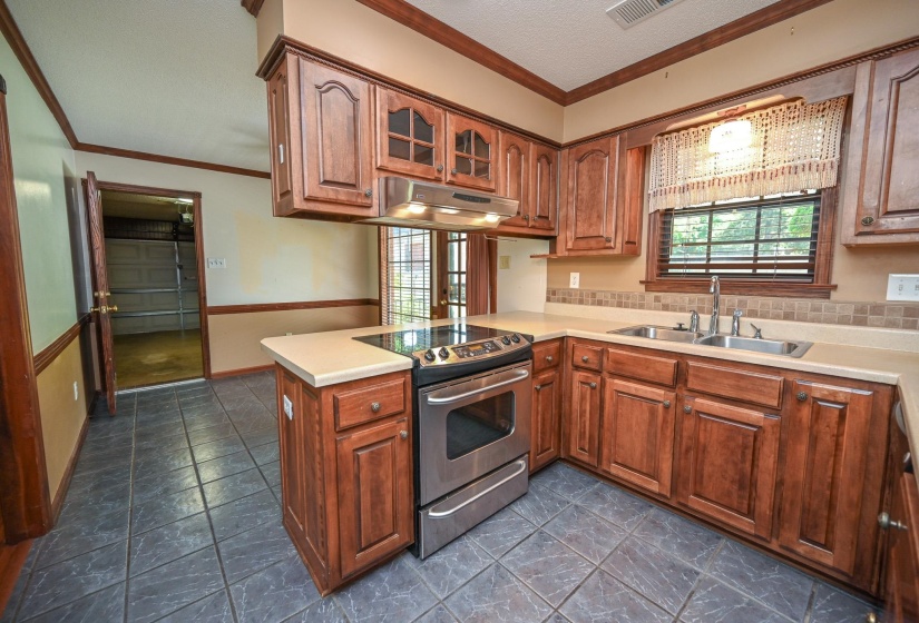 Kitchen featuring dark wood cabinetry, light countertops, a stainless steel range, and a dual basin sink.