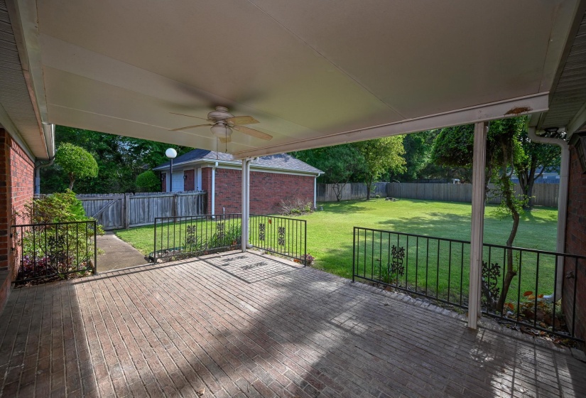 Peaceful back patio with brick flooring and ceiling fan is just waiting for those summer cookouts.