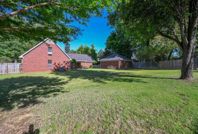 Expansive green lawn with mature trees providing natural shade.