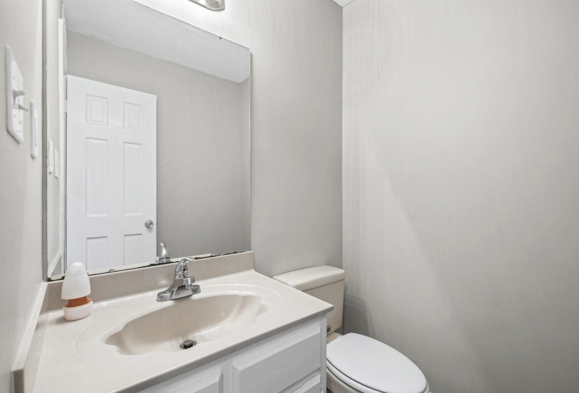 Bathroom vanity featuring an integrated sink, polished chrome faucet, and white base cabinetry