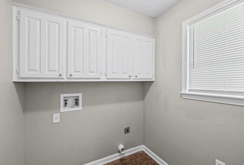 Utility room featuring white upper cabinetry, wood-finish flooring, and a window with blinds
