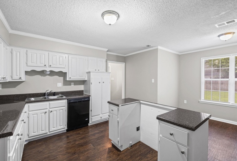 Kitchen featuring white cabinetry, dark speckled countertops, wood-finish flooring, and a built-in black dishwasher